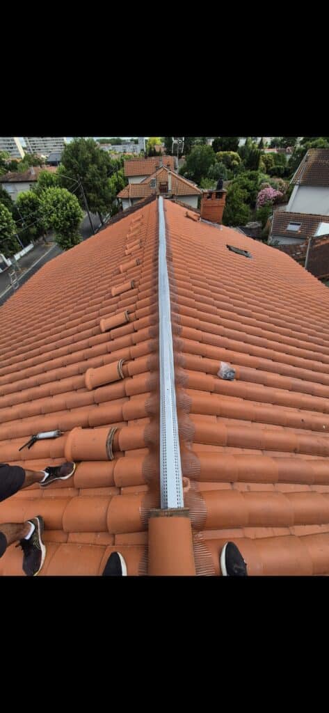 Rénovation de toiture : pose d'un closoir de faîtage Pose d'un closoir de faîtage ventilé sur un toit en tuiles terre cuite lors d'une rénovation de toiture.
