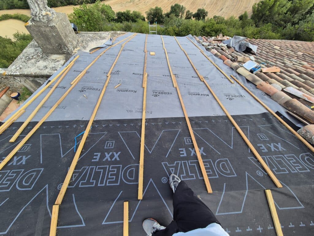 Rénovation de toiture : pose d'écran Delta-Maxx et liteaux Rénovation de toiture avec membranes Delta-Maxx et Koramic, liteaux bois verticaux et tuiles anciennes.